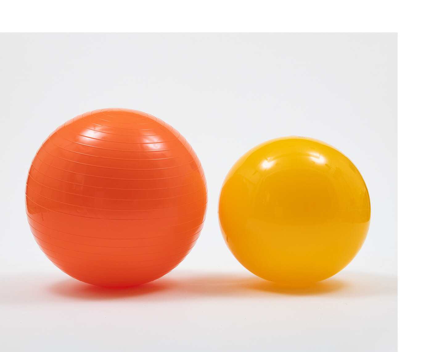 Zwei unterschiedlich große, farbige Plastikbälle stehen nebeneinander.
