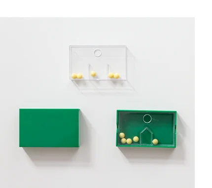 Das Set besteht aus einer grünen, aufschiebbaren Hülle aus Kunststoff, einem durchsichtigen Inlay und kleinen Kugeln, die durch ein Hindernnis getrennt werden können.