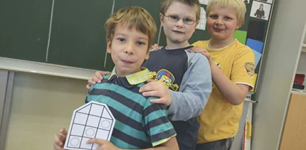 Drei Jungen hintereinander vor einer Schultafel
