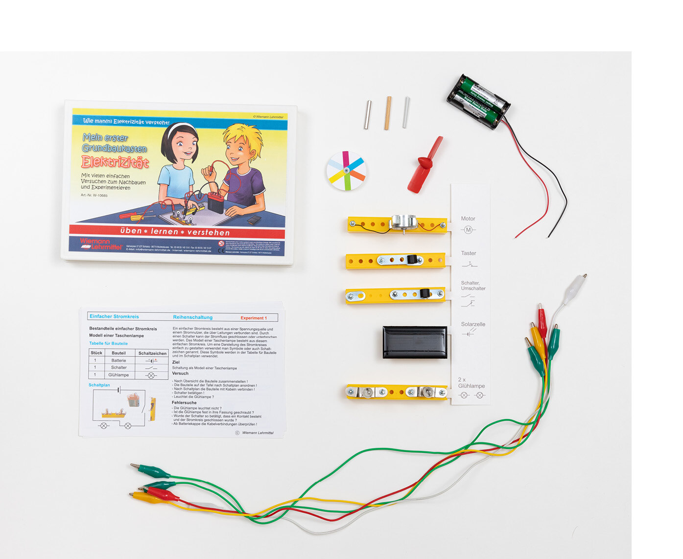 Bunte Kabel und verschiedene Bauteile liegen nebeneinander und sind entsprechend beschriftet. Außerdem ein Blatt, auf dem ein Experiment beschrieben ist.