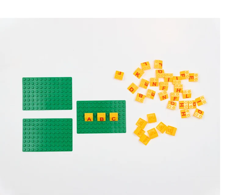 Drei grüne Platten, auf denen gelbe Bausteine mit Buchstaben darauf gesteckt sind.