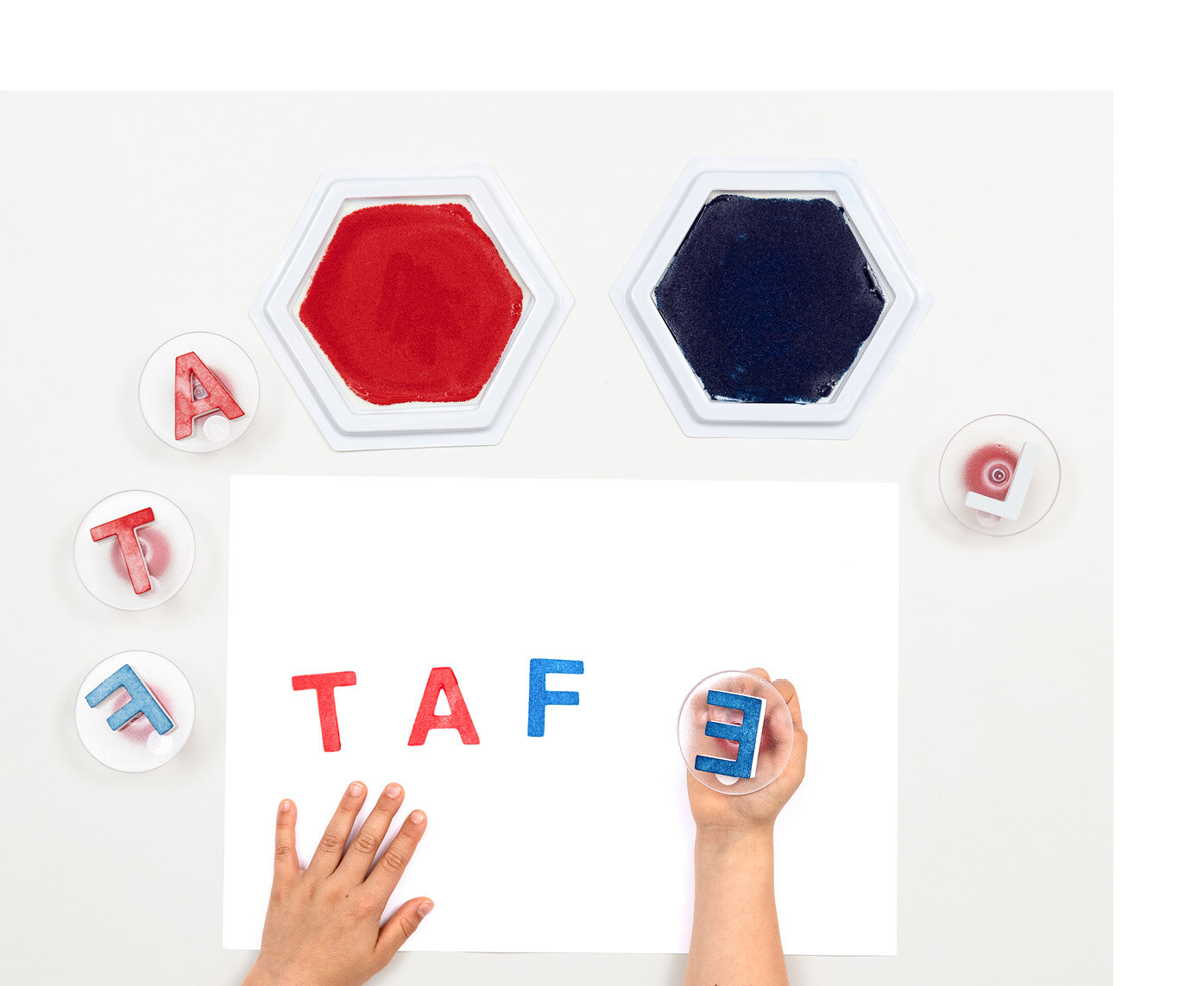 Verschiedene Stempel, ein weißes Blatt Papier und zwei Stempelkissen mit roter und blauer Farbe. 