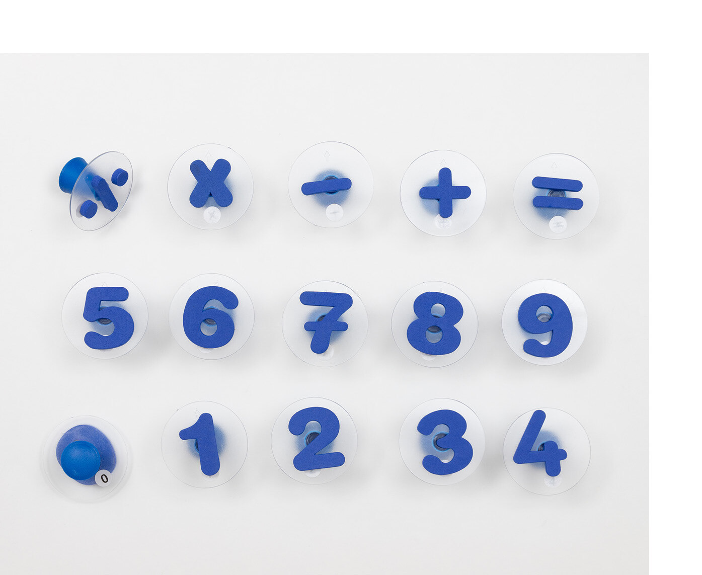 Auf einer Unterlage liegen dunkelblaue Plastikzahlen von eins bis neun in Form eines Stempels. Darüber liegen die Rechenzeichen geteilt durch, mal, minus, plus und istgleich. Ebenfalls in Form eines Stempels.