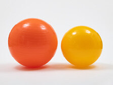 Zwei unterschiedlich große, farbige Plastikbälle stehen nebeneinander.