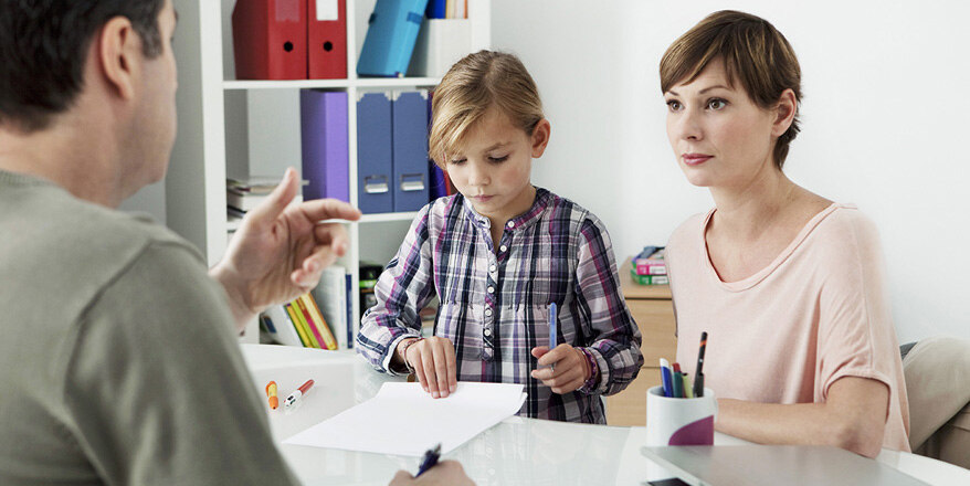 Eine Familie sitzt am Tisch und löst gemeinsam Hausaufgaben.