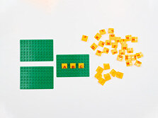 Drei grüne Platten, auf denen gelbe Bausteine mit Buchstaben darauf gesteckt sind.